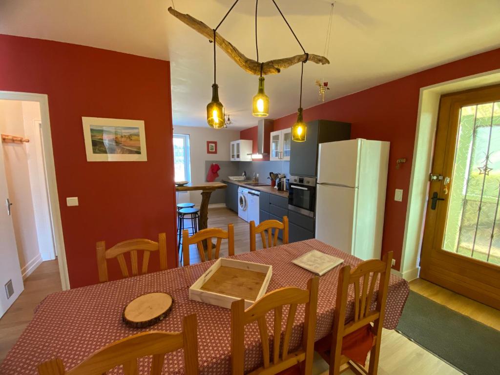 a kitchen and dining room with a table and a refrigerator at La grande marmite du lac de Vouglans in Pont-de-Poitte