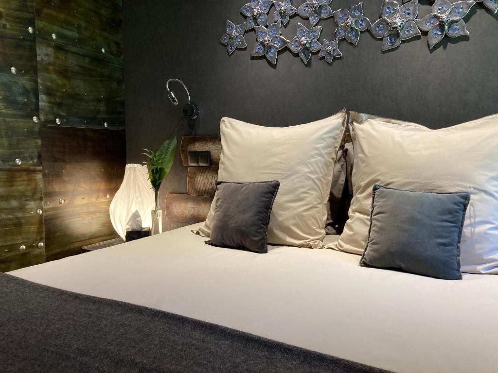 Un dormitorio con una cama blanca con almohadas y una lámpara de araña. en L'arbre à chapeaux, en La GrandʼCombe-Châteleu