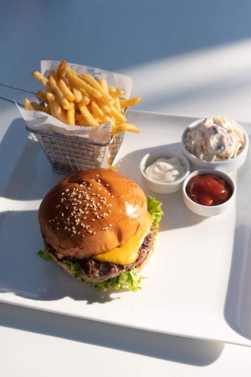 a plate with a hamburger and french fries and dips at Flamm in Golturkbuku