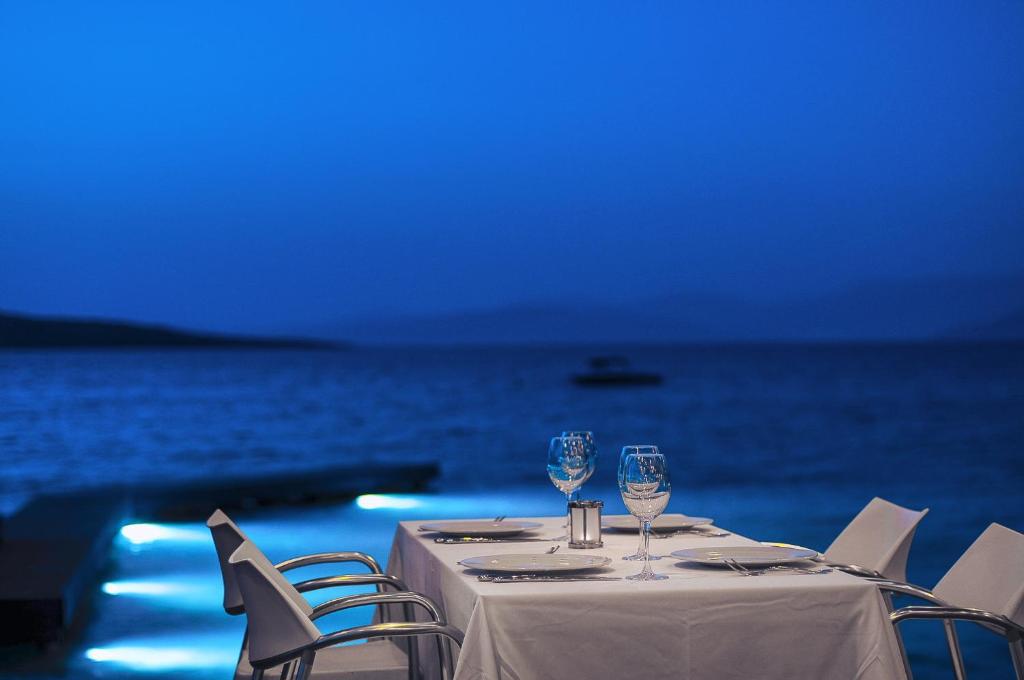 a table with two wine glasses and chairs next to the ocean at Flamm in Golturkbuku