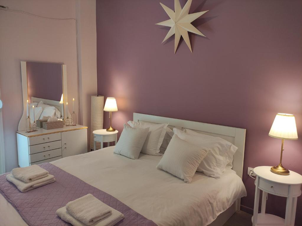 a bedroom with a white bed with two lamps and a mirror at Love Truth Life in Piraeus