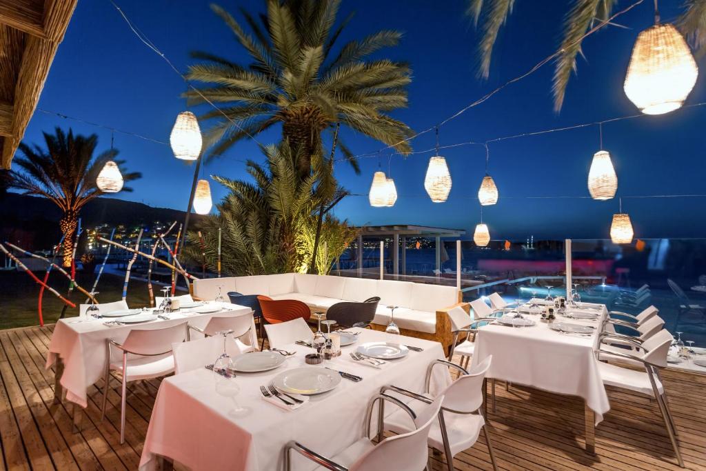 a restaurant with white tables and chairs and lights at Flamm in Golturkbuku