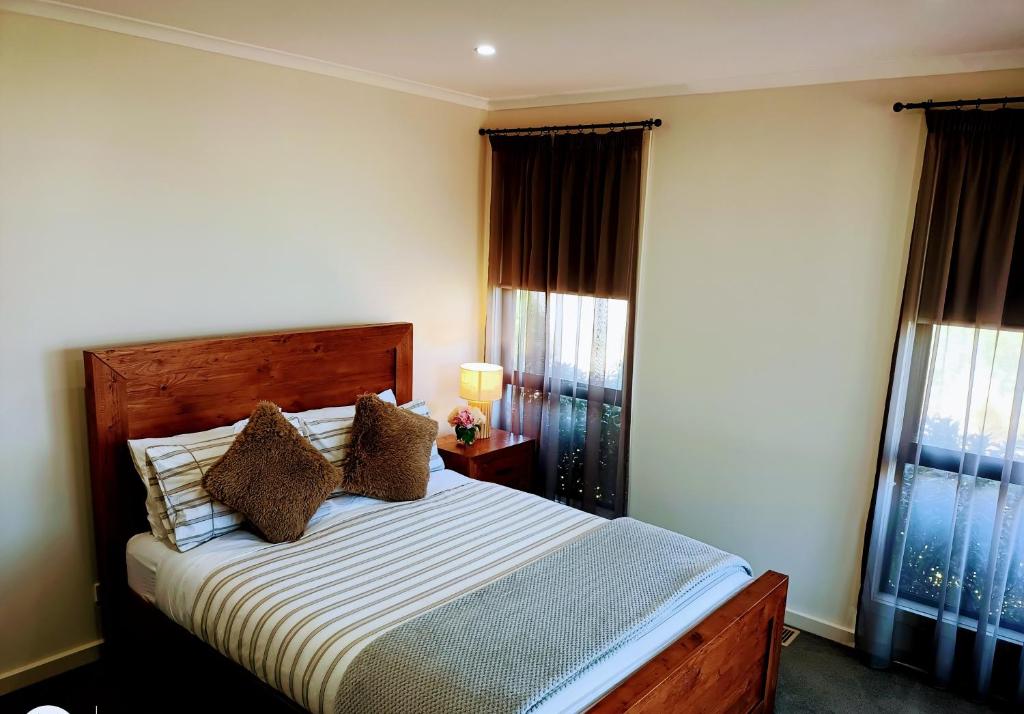a bedroom with a bed and two windows at London Bridge Holiday Home in Port Campbell