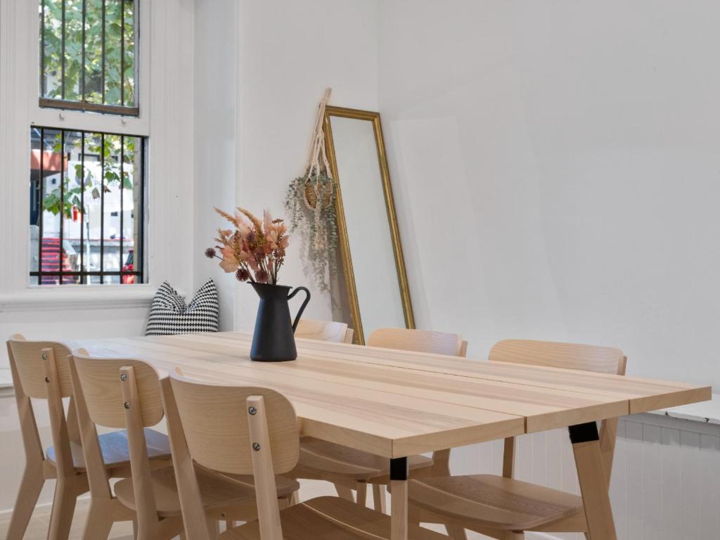 a dining room table with chairs and a vase with flowers at VENUS Potts Point - FEMALE ONLY HOSTEL - Long stay negotiable in Sydney