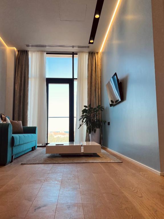 sala de estar con sofá azul y ventana grande en Baku, SEA BREEZE on the shores of the Caspian Sea, en Bilgah