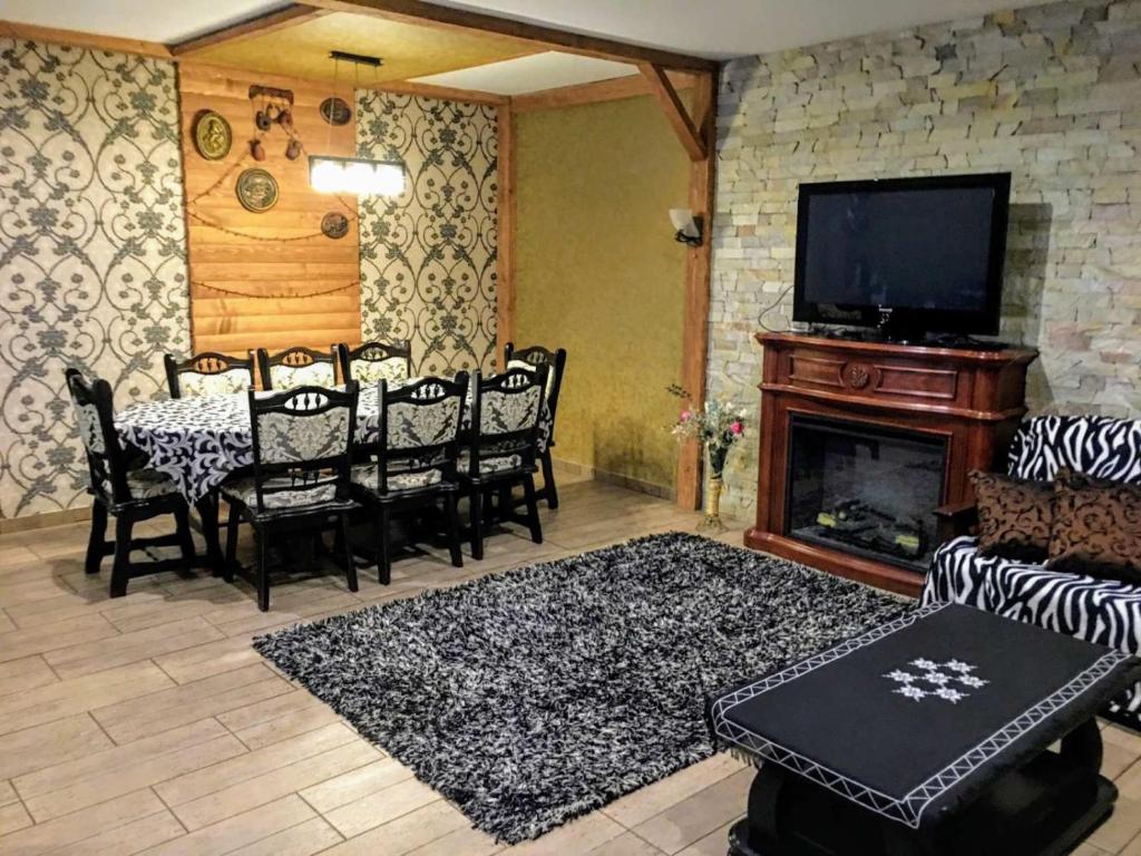 - un salon avec une table, des chaises et une cheminée dans l'établissement Уютнейший мини-отель "Rosky", à Yasinya