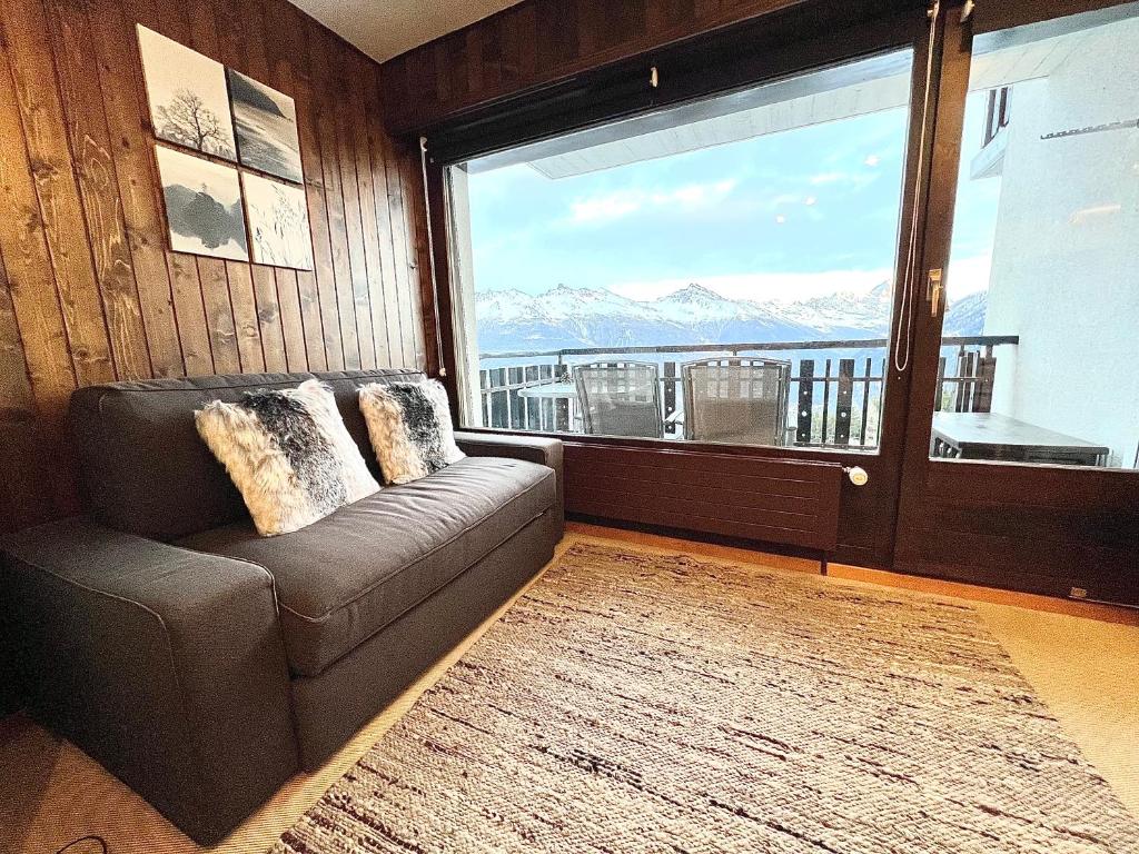 - un salon avec un canapé et une grande fenêtre dans l'établissement Cosy Studio for 5 near ski lift, Les Gentianes, à Les Collons