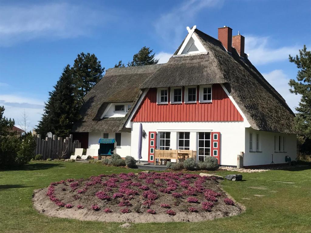 a house with a thatched roof and a bed of flowers at Landhaus Kranichblick in Wieck