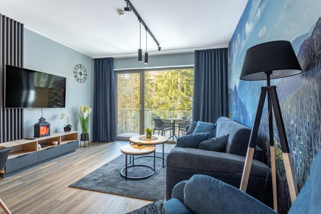 a living room with a couch and a tv at Stone Hill Apartament Wellness z basenem jakuzi saunami prywatnym garażem i rowerami w cenie in Szklarska Poręba