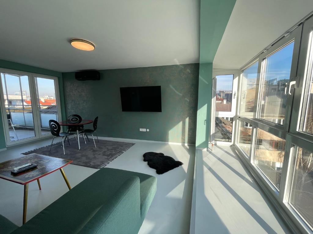 ein Wohnzimmer mit einem Sofa, einem Tisch und einem TV in der Unterkunft Amazing penthouse in Sarajevo