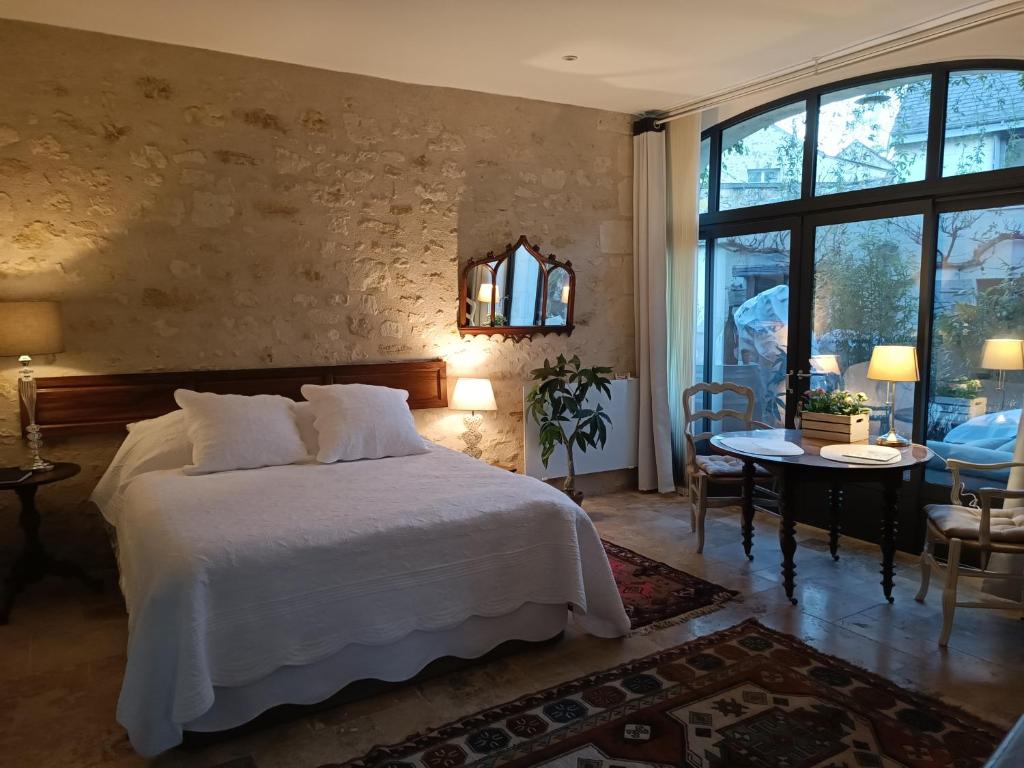 ein Schlafzimmer mit einem großen weißen Bett und einem Tisch in der Unterkunft Gîte la comète in Chinon