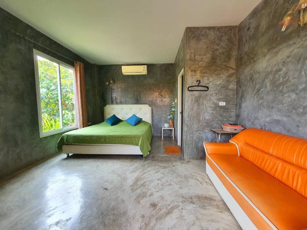 a bedroom with a green bed and a window at Bansuanrimnam Pakchong Resort in Pak Chong