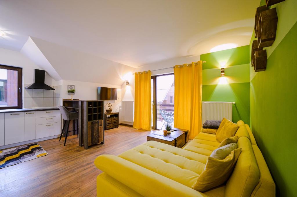 ein Wohnzimmer mit einem gelben Sofa und einer Küche in der Unterkunft Forest Nest with mountain view in Buşteni