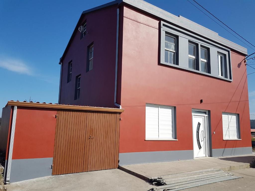 ein rotes und orangefarbenes Gebäude mit einer Garage in der Unterkunft Casa Campaña in Muxia