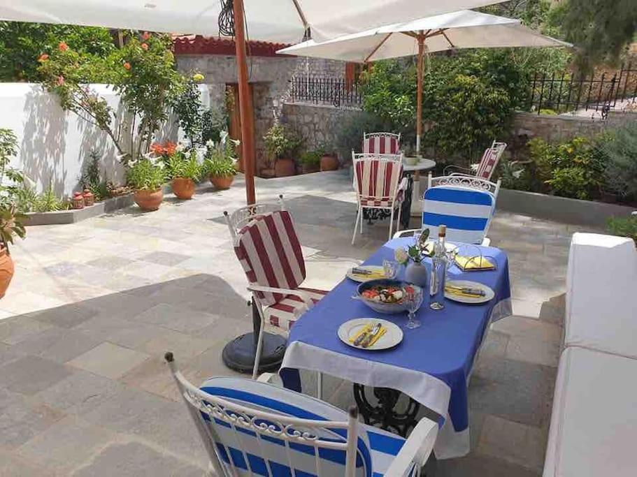 a table with chairs and an umbrella on a patio at Christiana’s Stone Villa in Hydra