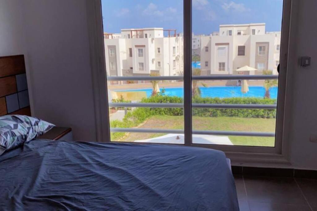 - une chambre dotée d'une fenêtre offrant une vue sur la piscine dans l'établissement Sidi Abd El-Rahman Amwaj duplex HUGE garden pool., à El Alamein