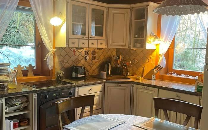 a kitchen with white cabinets and a table with chairs at Chata Lišiačik in Tajov