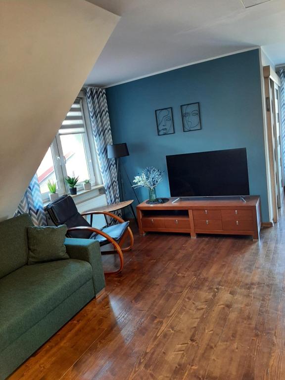 Il comprend un salon doté d'un canapé vert et d'une télévision à écran plat. dans l'établissement Apartament Gdańsk'a, à Nowy Dwór Gdański