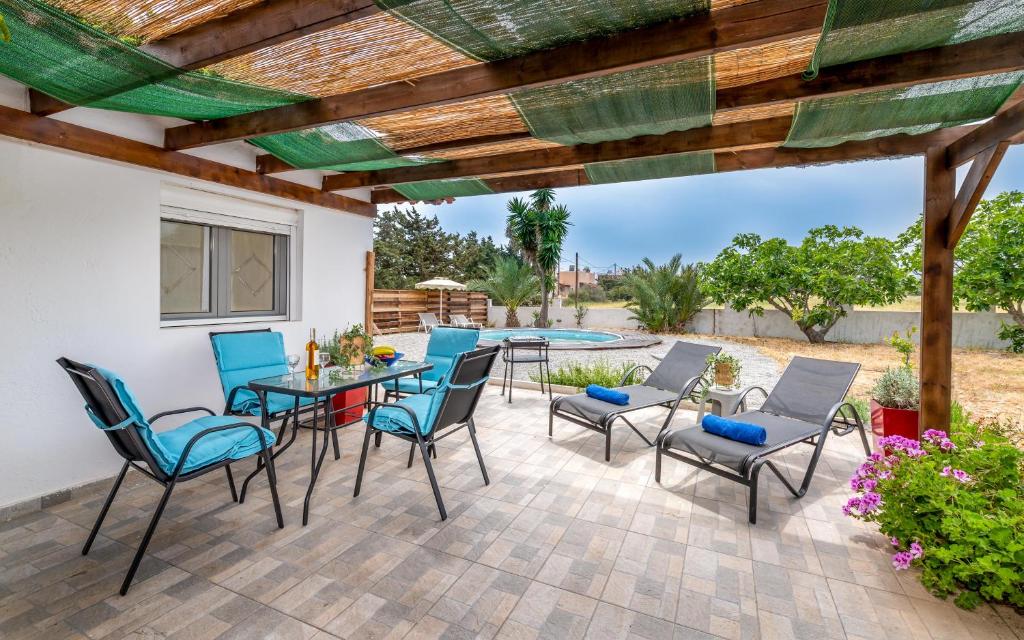 a patio with a table and chairs under a wooden pergola at Cavo Prima Kiotari in Gennadi