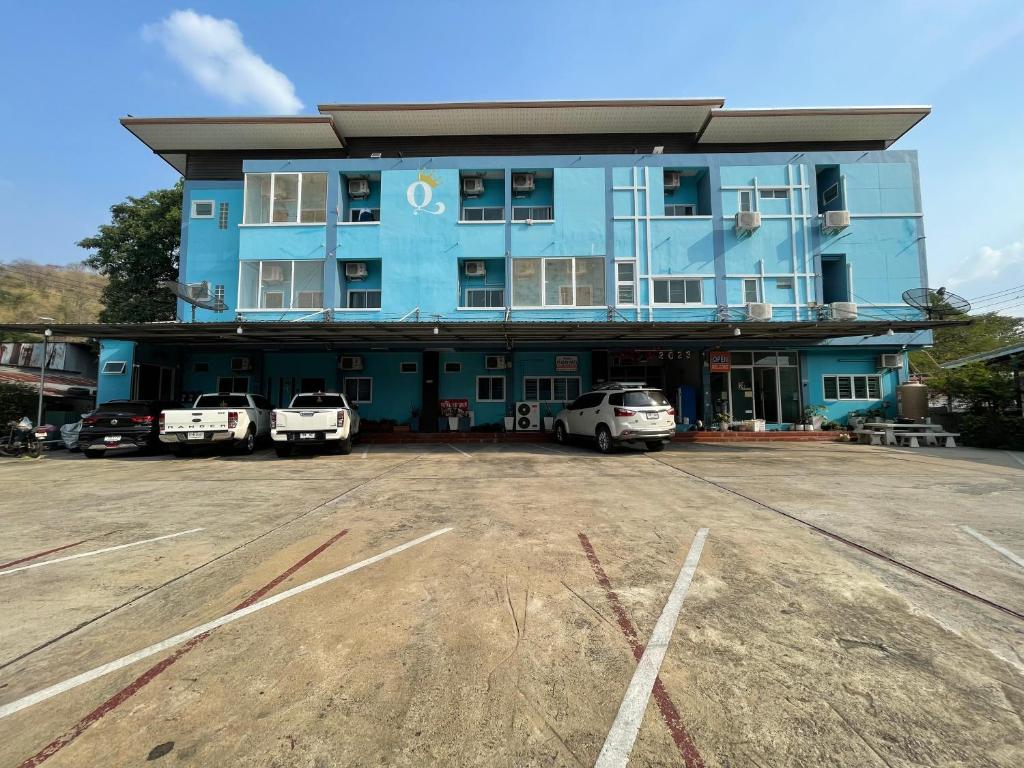 a blue building with cars parked in a parking lot at ควีนเพลส สระบุรี Queenplace Saraburi in Sara Buri