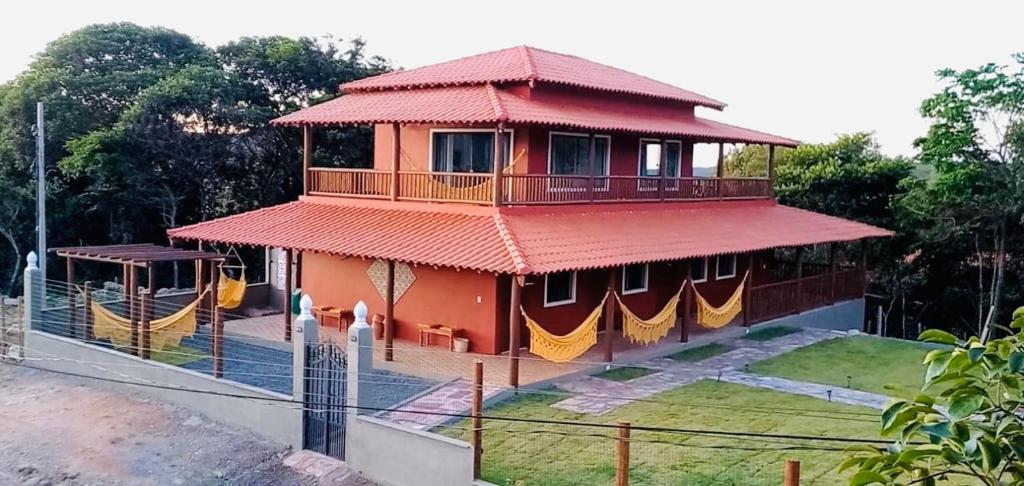 a house with a red roof with a balcony at Casa Passarinho - Vale do Capão in Vale do Capao