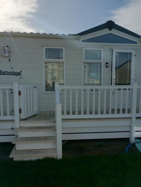 ein Haus mit einem weißen Zaun und einer Veranda in der Unterkunft Luxury 2 bedroom caravan with large decking Close to beach in Abergele