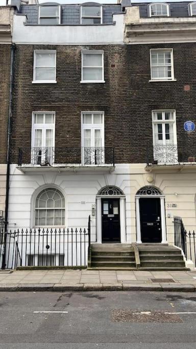 duży ceglany budynek z czarnymi drzwiami na ulicy w obiekcie Amazing Central London Apartment w Londynie
