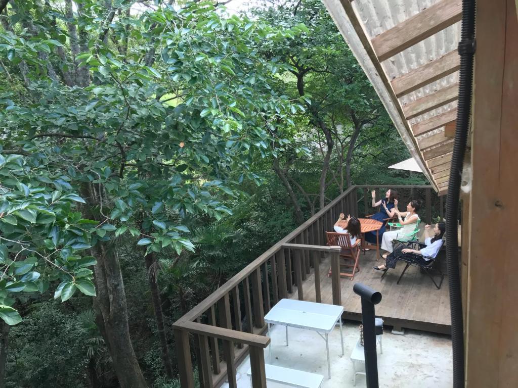 a group of people sitting at tables on a porch with trees at かげやんのいえ　KAGEYAN NO IE in Tsu