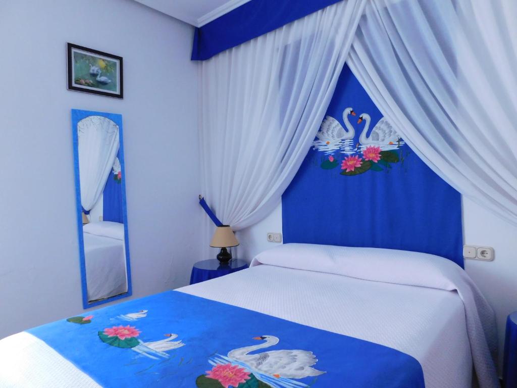 a blue and white bedroom with a bed and a mirror at Casa de la Abuela Pepa in Zafarraya