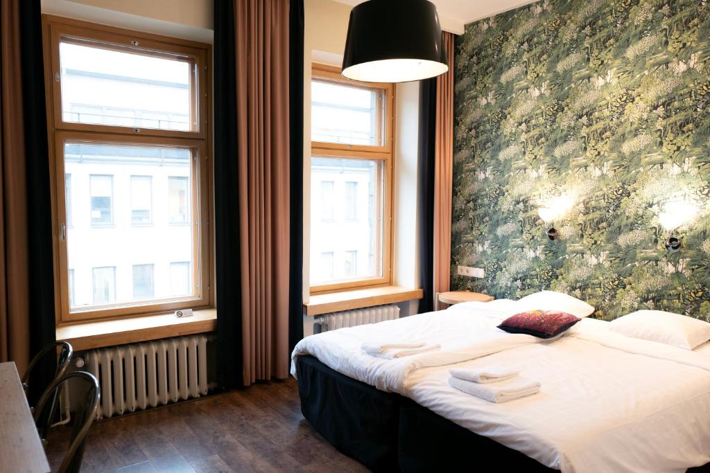 ein Schlafzimmer mit einem Bett und zwei Fenstern in der Unterkunft Hotel Finn in Helsinki