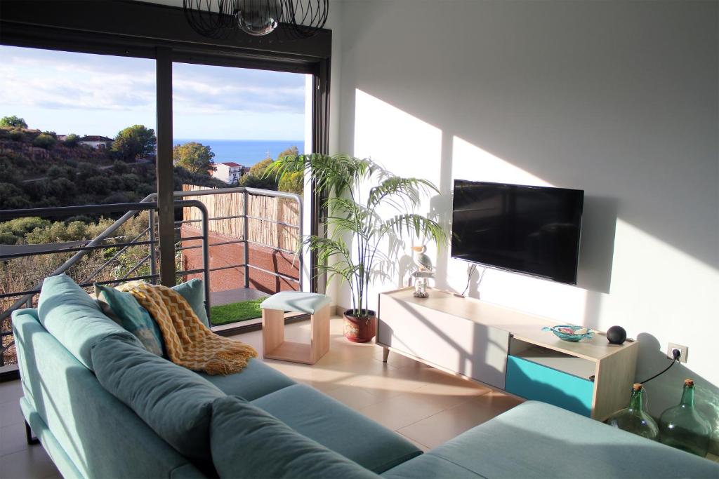 - un salon avec un canapé bleu et une grande fenêtre dans l'établissement Home of the Sun - Luminoso adosado con vistas al mar y a 2 km de la playa, à Vélez-Málaga