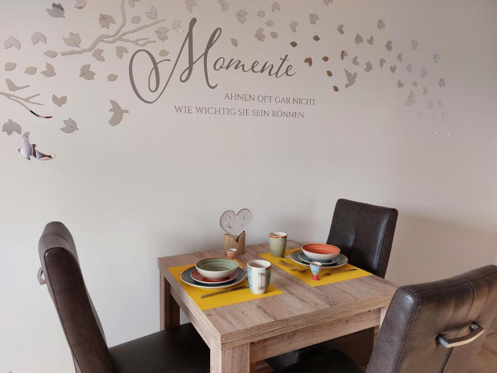 a dining room table with aania sign on a wall at Trekvogels Utkiek in Dornum