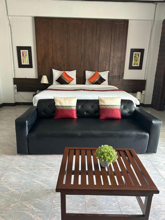 A double room with a black leather sofa and wood coffee table facing the bed.