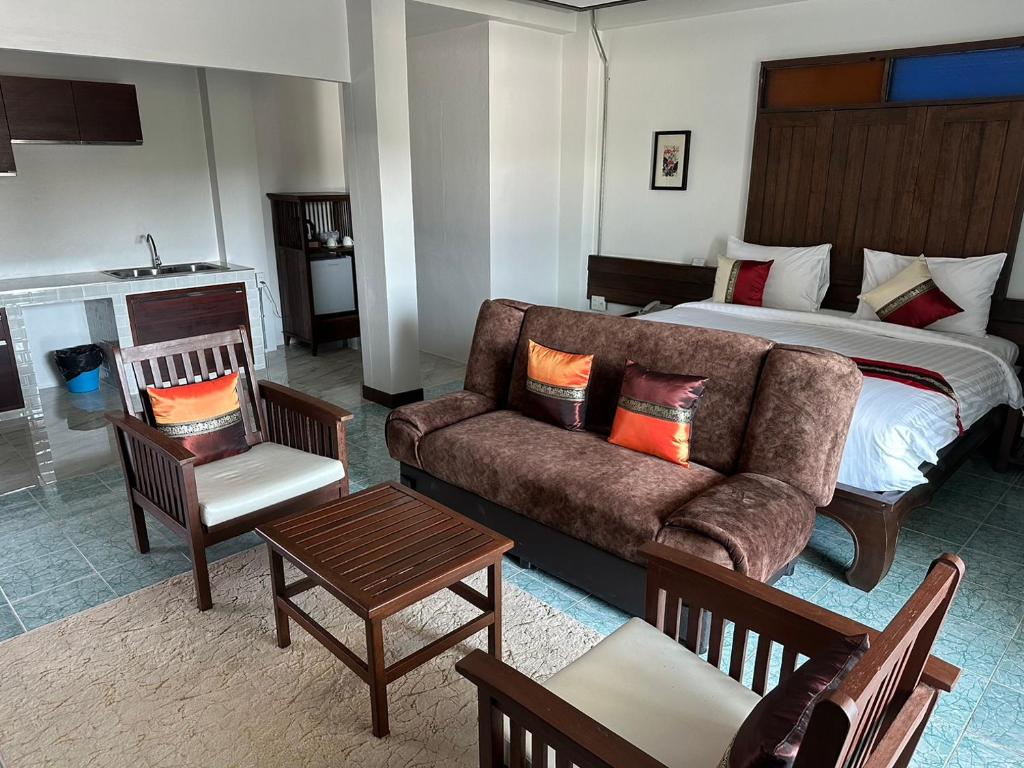 A bedroom-living area with a double bed, sofa, dining chairs and a compact kitchenette.