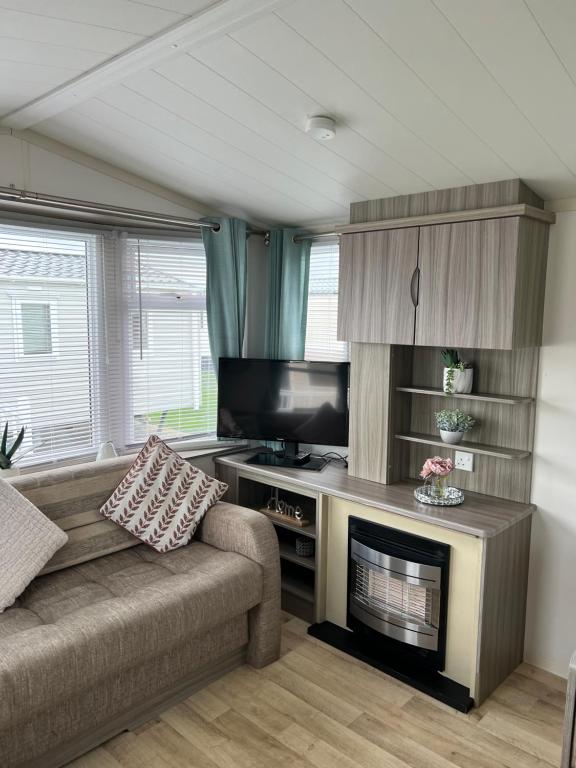 a living room with a couch and a fireplace at Millie’s caravan in Abergele