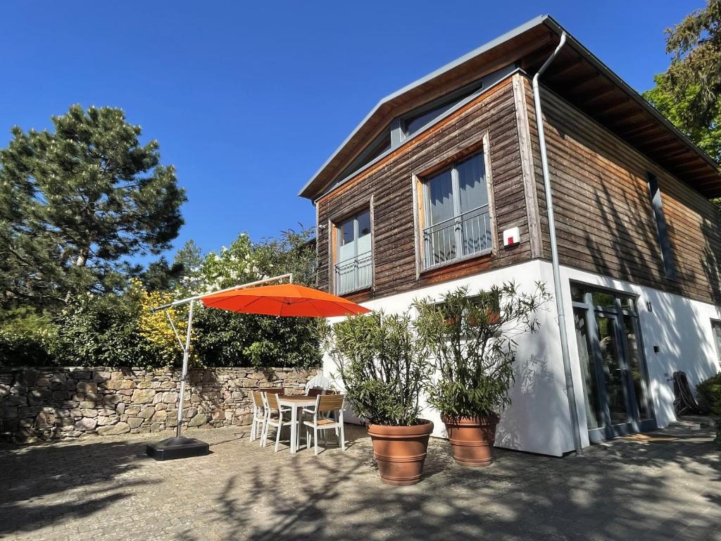 une maison avec un parasol orange, une table et des chaises dans l'établissement BALTHASAR RESS Guesthouse am Rebhang im Rheingau, à Oestrich-Winkel