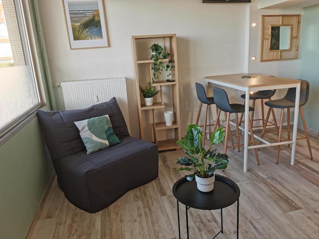 a living room with a couch and a table at Le Pouget , Studio, Rez de Chaussée, Front de Mer WIFI in Le Touquet-Paris-Plage