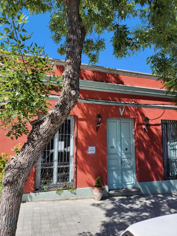 un edificio rojo con una puerta azul y un árbol en Casa Victoria, en Colonia del Sacramento