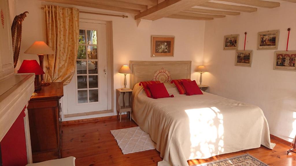 a bedroom with a bed with red pillows on it at A l'Ombre du Tilleul in Giverny