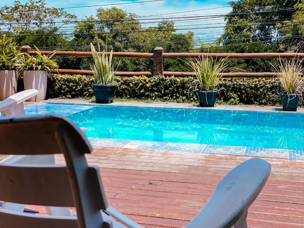 a chair next to a swimming pool with plants at Pousada Solar de Búzios in Búzios