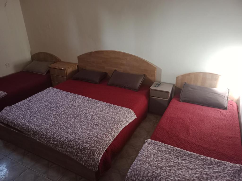 - une chambre avec 2 lits et des draps rouges dans l'établissement الجداوي Al-Jeddawi, à Aqaba