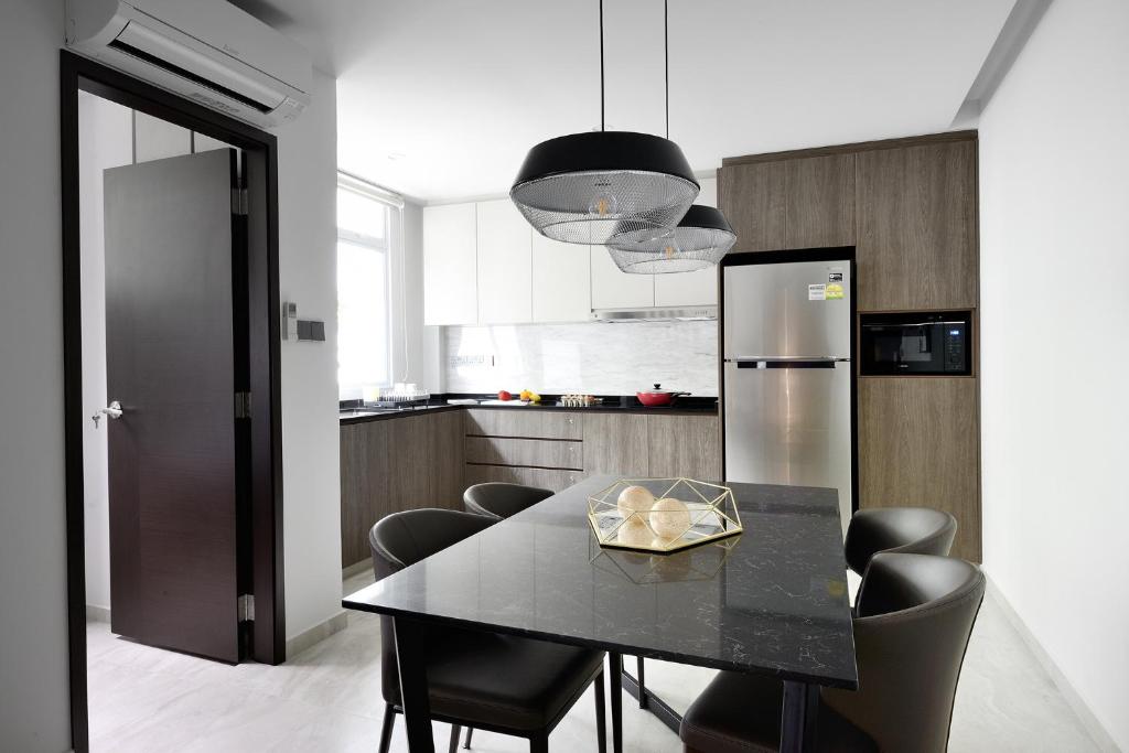 a kitchen with a black table with chairs and a refrigerator at The Assembly Place at Stevens, Service Residences in Singapore