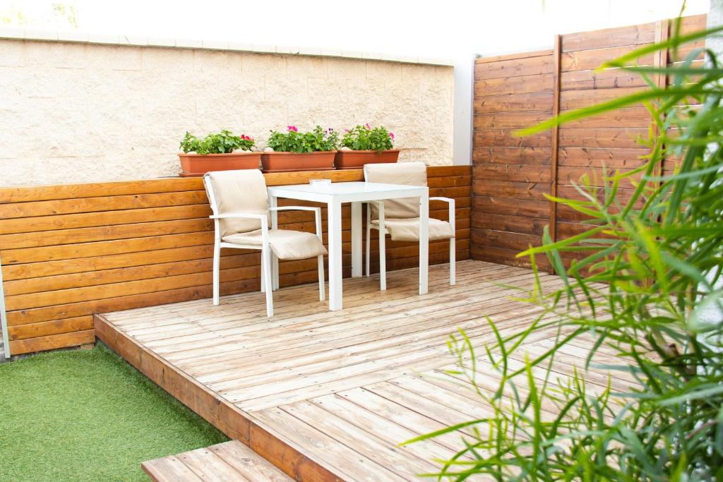 een witte tafel en stoelen op een houten terras bij Stacey’s Stylish studio in Eilat