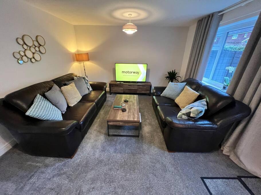a living room with two leather couches and a tv at Very comfy 3 bed town house in Ashton under Lyne