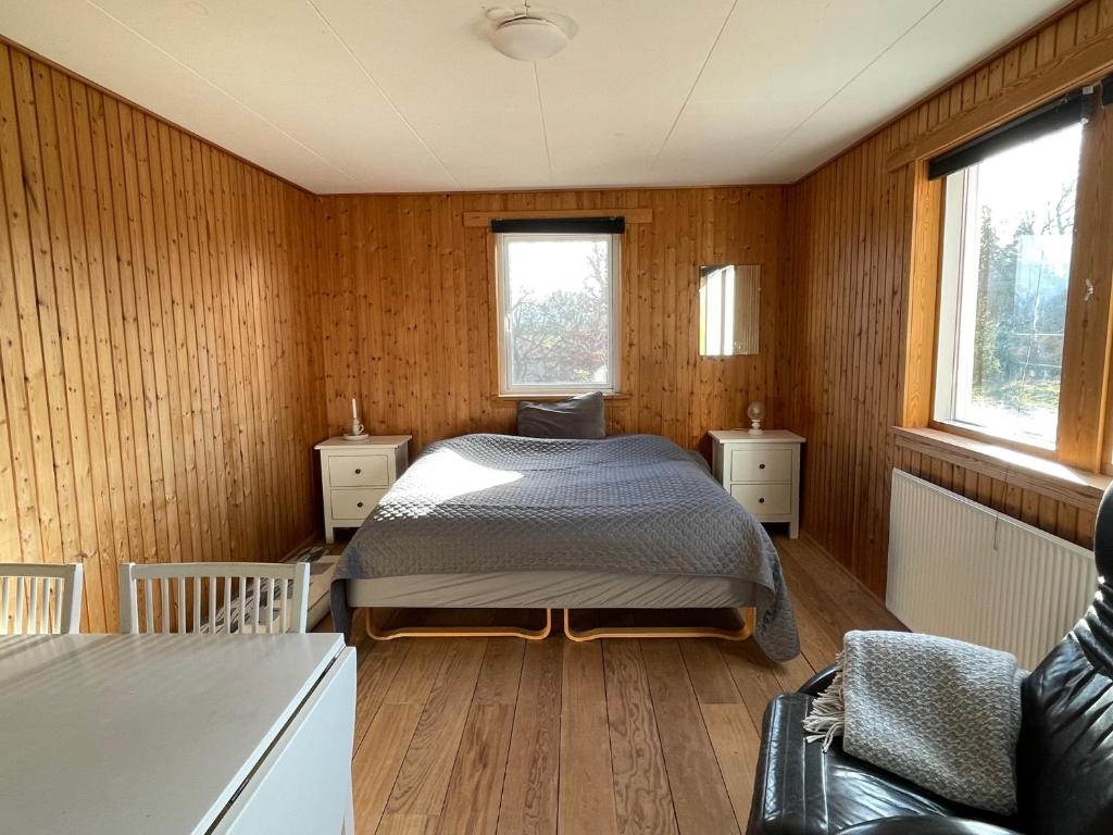 een slaapkamer met een bed in een kamer met houten wanden bij Eskærhus på Tåsinge, tæt på Svendborg - Afdeling med egen indgang in Troense