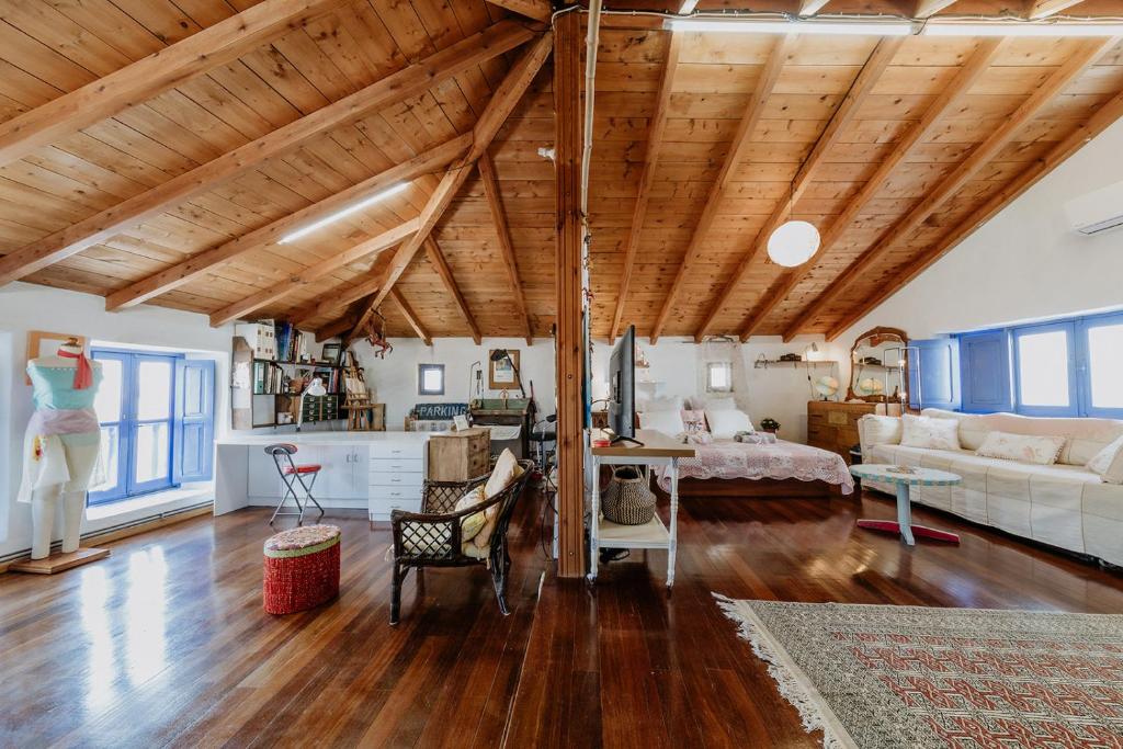 ein Wohnzimmer mit Holzdecken und ein Zimmer mit einem Bett in der Unterkunft Artistic Home- 250yr old traditional village house in Koskinou