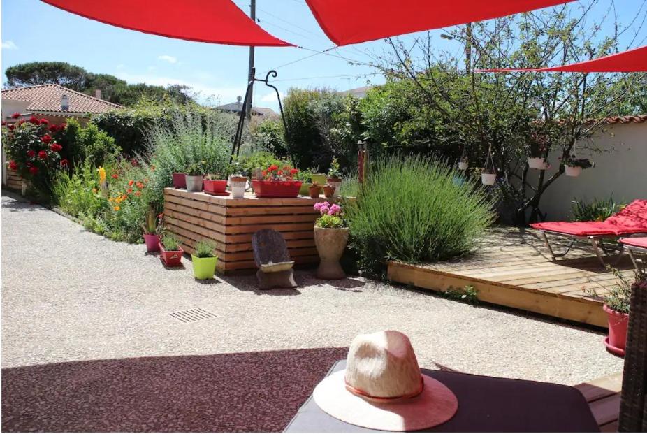 um jardim com um guarda-chuva vermelho e algumas plantas em La Cotinière, studio avec cuisine 50 m de la plage em La Cotinière