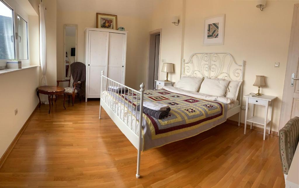a bedroom with a white bed and a wooden floor at B&B LUCHICHI in Igalo