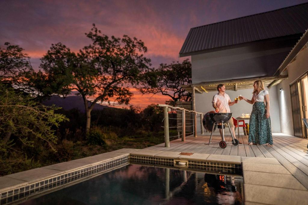 un homme et une femme debout sur une terrasse à côté d'une piscine dans l'établissement Kruger Cliffs Lodge, à Hoedspruit