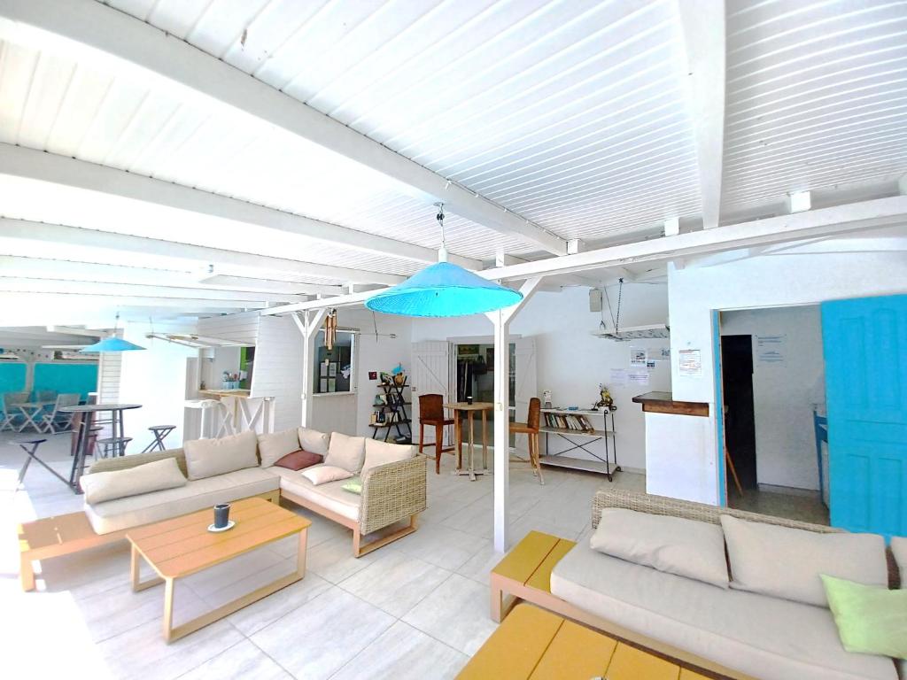 a living room with couches and a blue umbrella at La Rose du Bresil Marie-Galante in Capesterre